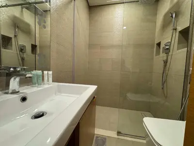 a bathroom with a sink and a glass shower at Furnished Studio in JVC Hassle-Free Living in Dubai