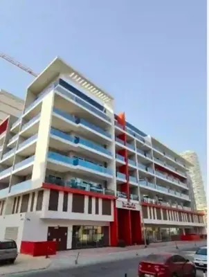 a large apartment building with cars parked in front of it at Furnished Studio in JVC Hassle-Free Living in Dubai