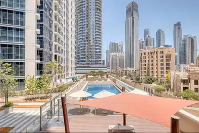 a swimming pool with umbrellas and a city skyline at Vogue Downtown Bellevue Towers near Burj Khalifa and Dubai Mall, One Bedroom Apartment with City View, Full Access to all Amenities in Dubai