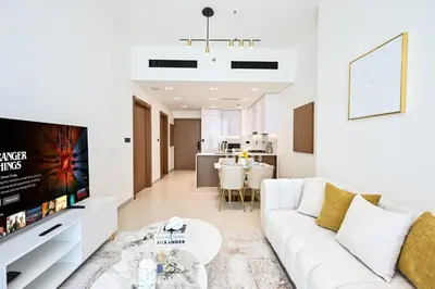 a living room with a white couch and a tv at Golden Stays - Binghatti Amber I Luxury 1BR Apartment I Fully Furnished I Pool & Gym in Dubai