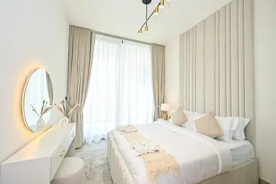 a white bedroom with a large bed and a mirror at Golden Stays - Binghatti Amber I Modern 1BR Apartment I Balcony, Pool & Gym Access in Dubai