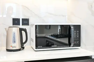 a microwave sitting on a counter with a coffee maker at Golden Stays - Binghatti Amber I Modern 1BR Apartment I Balcony, Pool & Gym Access in Dubai