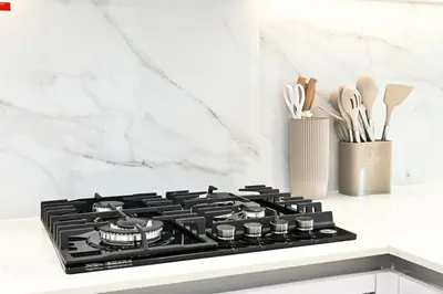 a black stove top oven in a white kitchen at Golden Stays - Binghatti Amber I Modern 1BR Apartment I Balcony, Pool & Gym Access in Dubai