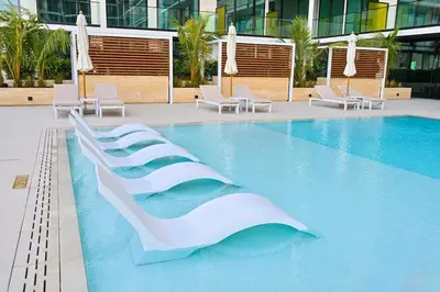 a swimming pool in a hotel with chairs at Golden Stays - Binghatti Amber I Modern 1BR Apartment I Balcony, Pool & Gym Access in Dubai