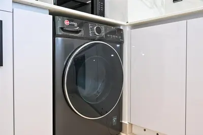 a washing machine in a cabinet in a kitchen at Golden Stays - Binghatti Amber I Modern 1BR Apartment I Balcony, Pool & Gym Access in Dubai