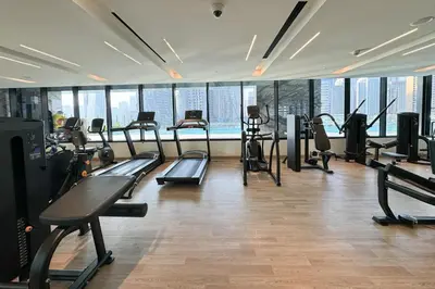 a gym with treadmills and machines in a room with windows at Comfortable 2 Bedroom in Business Bay in Dubai