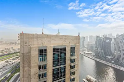 a tall building next to a river with buildings at Comfortable 2 Bedroom in Business Bay in Dubai
