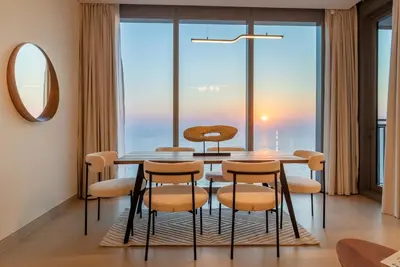 a dining room with a table and chairs and a large window at Luxury 2 BHK in Jumeirah By dPie Emaar 2008 in Dubai