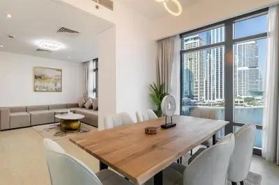 a living room with a wooden table and chairs at Luxury 2BHK Stunning Skyline Lakeview in JLT 401 in Dubai