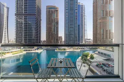 a balcony with a table and chairs and a view of a city at Luxury 2BHK Stunning Skyline Lakeview in JLT 401 in Dubai