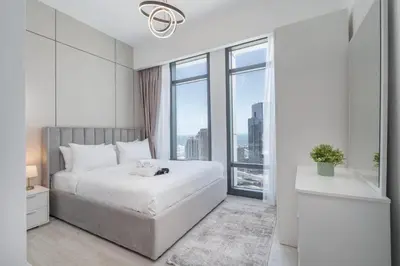 a white bedroom with a large bed and a window at Luxury 2BHK in Jumeirah Late Towers JLT 2609 in Dubai