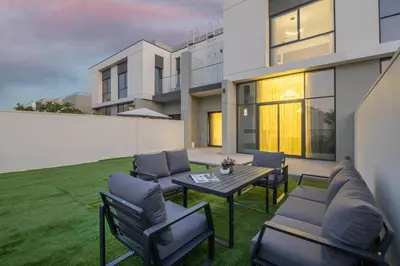 a patio with chairs and a table on a lawn at Luxury Villa in Jebel Ali Village By dPie in Dubai