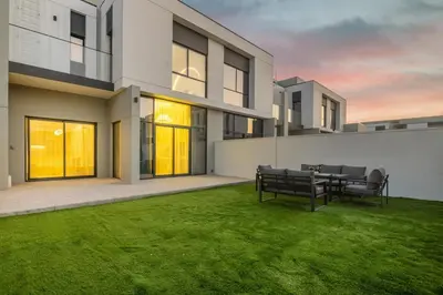 a house with a green yard with a table and benches at Luxury Villa in Jebel Ali Village By dPie in Dubai