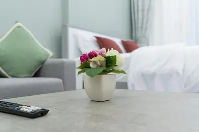 a vase with flowers on a table next to a remote control at Dubai Marina - Perfect Studio Apartment in Dubai
