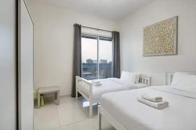 a hotel room with two beds and a window at Bright 2BR Sports City Near Miracle GardenParks in Dubai