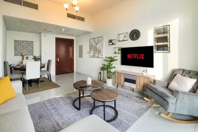 a living room with a couch and a tv at Bright 2BR Sports City Near Miracle GardenParks in Dubai