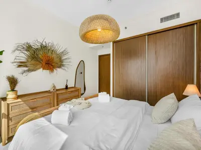 a bedroom with a large white bed and a mirror at Chic 1 Bedroom with Palm Views in Palace Beach Residence in Dubai