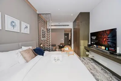 a bedroom with a large white bed with a flat screen tv at Canal View Studio near Dubai Mall in Dubai