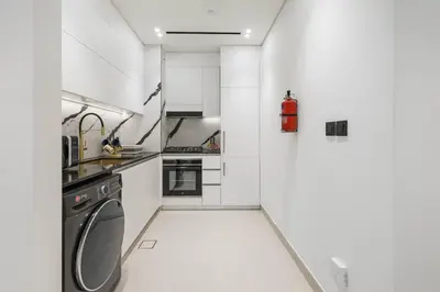 a white kitchen with a washer and dryer at BLVD Retreat - Luxury Oasis with Private Jacuzzi and Iconic Burj Khalifa Views in Dubai