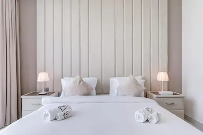 two beds in a bedroom with two lamps on tables at PVH - Lagoon View 1BR - District One in Dubai