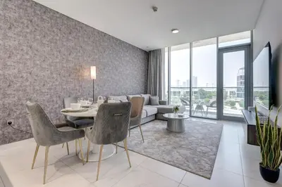 a living room with a table and a couch at PVH - Lagoon View 1BR - District One in Dubai