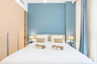 a bedroom with a large white bed with two lamps at Creek Home with Private Terrace & Direct Pool Access in Dubai