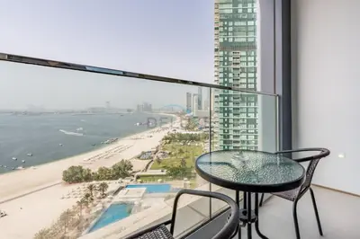 a balcony with a table and chairs and a view of the beach at 3BR Overlooking Sea, Ain Dubai, and Bluewaters Island, Walking Distance to the Beach, The Address Residences, Jumeirah Beach Residence by Deluxe Holiday Homes in Dubai