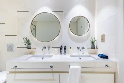 a white bathroom with two sinks and two mirrors at Luxury Stay, 3BR Palm View, Beach Vista in Dubai