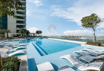 a swimming pool with white lounge chairs next to a building at Luxury Stay, 3BR Palm View, Beach Vista in Dubai