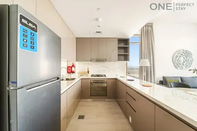 a kitchen with white counters and a stainless steel refrigerator at Modern 1-Bedroom Apartment in Al Furjan With Pool & Gym in Dubai