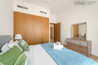 a bedroom with a bed with a dresser and a mirror at Modern 1-Bedroom Apartment in Al Furjan With Pool & Gym in Dubai