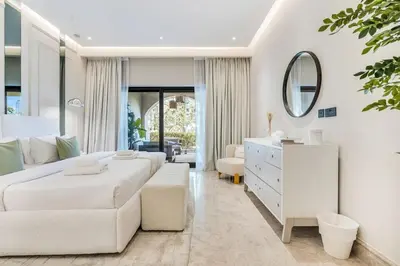 a white bedroom with two beds and a mirror at DAYF-FMT Fairmont Palm with Pool and Beach Access in Dubai