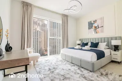 a bedroom with a large bed and a desk and a window at Newly Furnished, Beach Access located in La Vie, JBR in Dubai