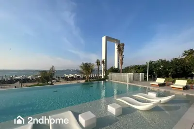 a swimming pool with white chairs and the ocean at Newly Furnished, Beach Access located in La Vie, JBR in Dubai