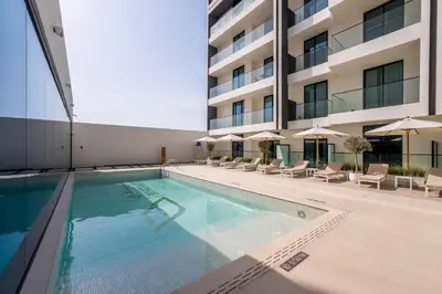 a swimming pool in front of a building at New! Stylish Studio with Pool, Gym & Jacuzzi, JVC in Dubai