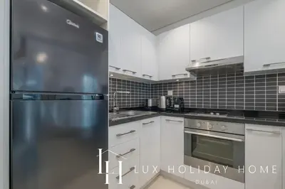 a kitchen with white cabinets and a stainless steel refrigerator at LUX The Silverene Marina View Studio 2 in Dubai