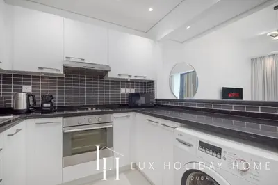 a white kitchen with white cabinets and a mirror at LUX The Silverene Marina View Studio 2 in Dubai