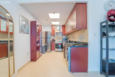 a large kitchen with wooden cabinets and appliances at Gardenia Bahar Suites 1 Bedroom Apartment in JBR with 2 mins walk to the Beach in Dubai
