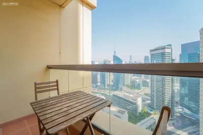 a wooden table and chairs on a balcony with a view at Gardenia Bahar Suites 1 Bedroom Apartment in JBR with 2 mins walk to the Beach in Dubai