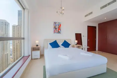 a bedroom with a large white bed and large windows at Gardenia Bahar Suites 1 Bedroom Apartment in JBR with 2 mins walk to the Beach in Dubai