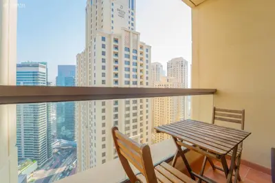 a table and chairs on a balcony with a view of a city at Gardenia Bahar Suites 1 Bedroom Apartment in JBR with 2 mins walk to the Beach in Dubai