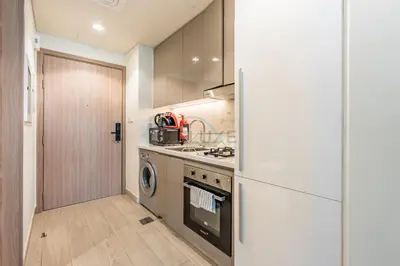 a kitchen with a stove and a refrigerator at Furnished Studio Near Meydan Racecourse, Minutes to Downtown Dubai, Azizi Riviera 47, Al Merkadh by Deluxe Holiday Homes in Dubai