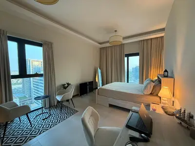 a bedroom with a bed and a desk with a laptop at Luxury Stay Dual View Furnished Swimming Pool Gym in Dubai