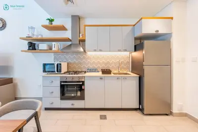 a kitchen with white cabinets and stainless steel appliances at Blue Breeze - Modern 1BR, Dubai Hills, in Dubai