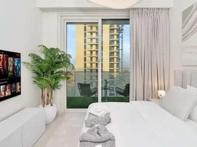 a bedroom with a white bed and a large window at Palm and Marina Views in NEW Palace Beach Residence in Dubai