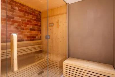 a sauna with a glass shower stall and a bench at NEW 2 Bed w Rooftop Pool Panoramic Dubai Views in Dubai