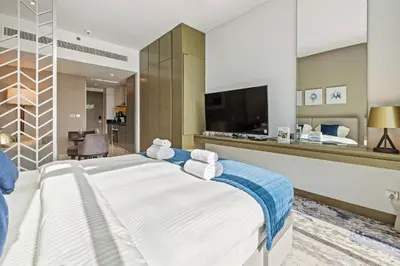 a bedroom with a large white bed and a television at BLVD - Stunning Canal View - 5 Minutes from Burj Khalifa in Dubai