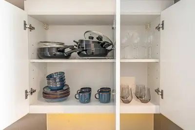 a cupboard with plates and dishes and a pot and pans at BLVD - Stunning Canal View - 5 Minutes from Burj Khalifa in Dubai
