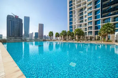 a large blue swimming pool with palm trees and buildings at BLVD - Stunning Canal View - 5 Minutes from Burj Khalifa in Dubai