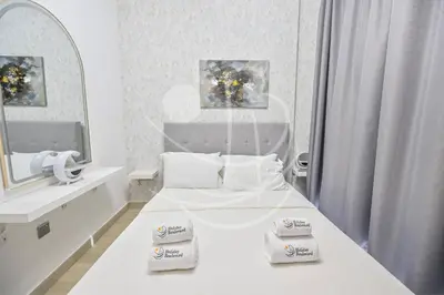 a white bedroom with two beds and a mirror at Modern Cozy 1BR Retreat Azizi Riviera Dubai in Dubai